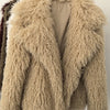Beige fluffy jacket on a hanger against a white wall