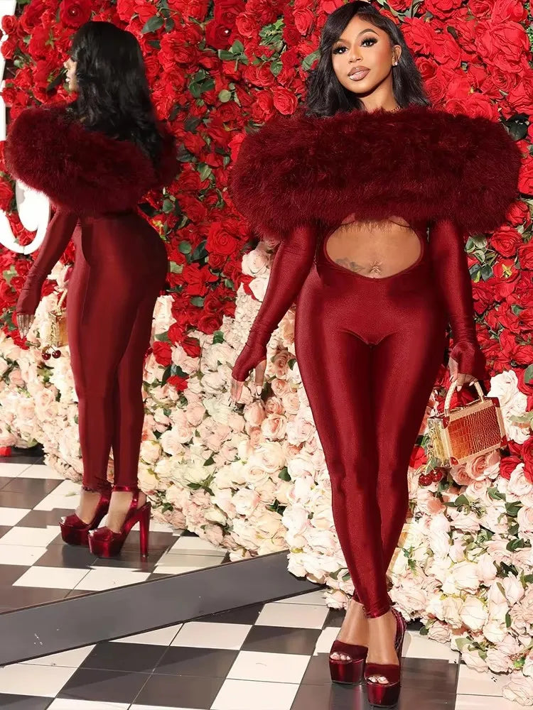 Woman in a red outfit with a fur collar standing in front of a floral wall.