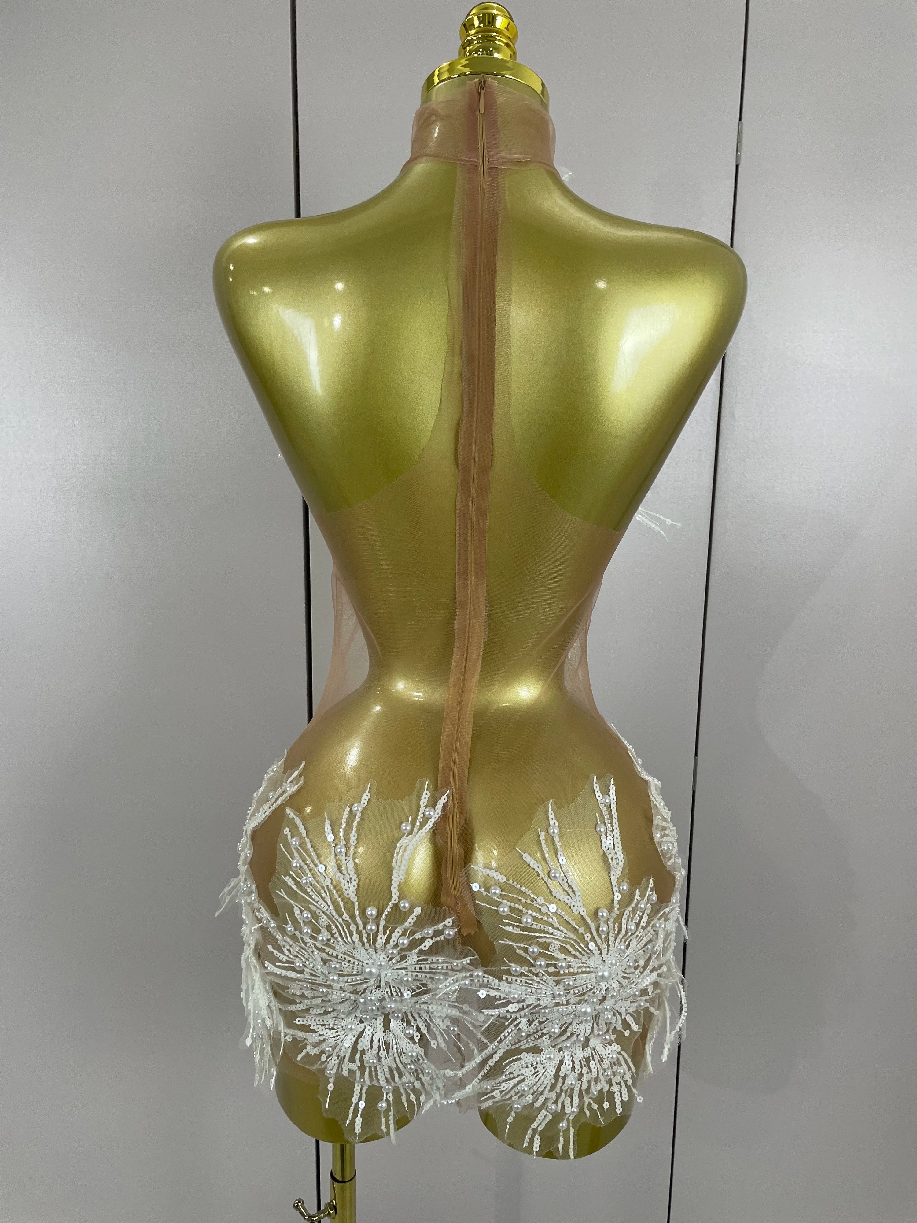 Gold mannequin wearing a sheer white bikini with floral details against a plain background