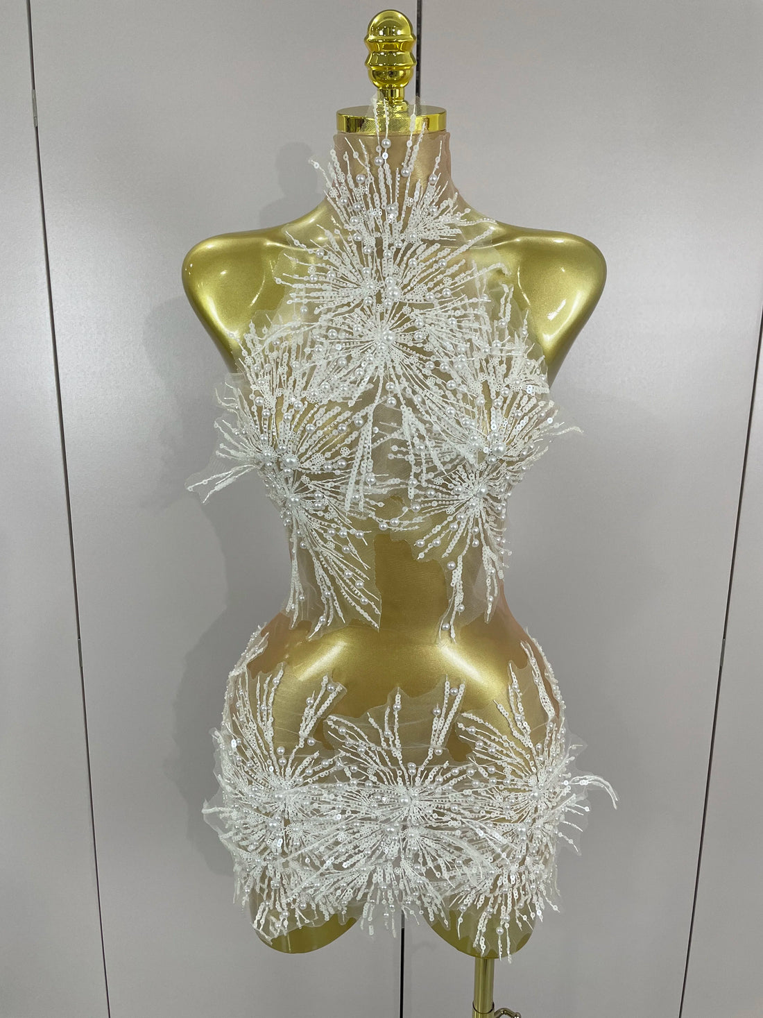 Mannequin wearing a sparkling white dress against a plain background