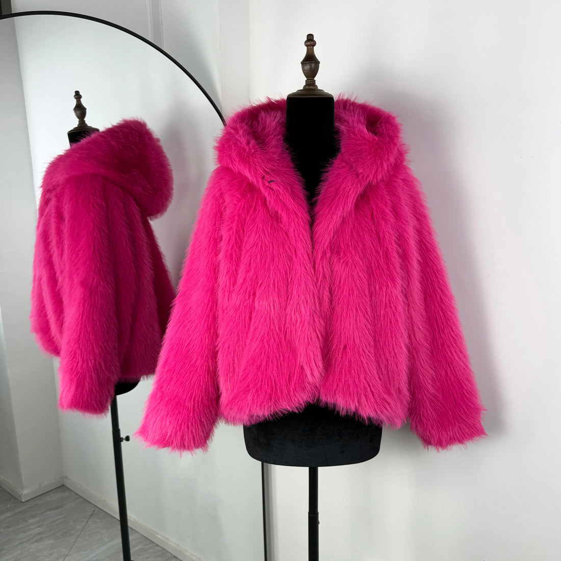 Hot pink fur coat on a mannequin against a white background